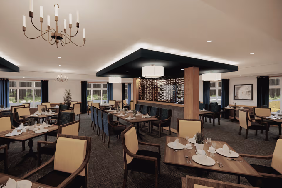 A spacious dining room with multiple wooden tables set with white plates, cups, and napkins. The chairs have beige cushions and dark wooden frames. The room features large windows with dark curtains, modern chandeliers, and ceiling lights. A decorative wooden partition separates part of the room.