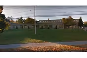 Exterior view of a single-story nursing center with a grassy lawn and power lines.