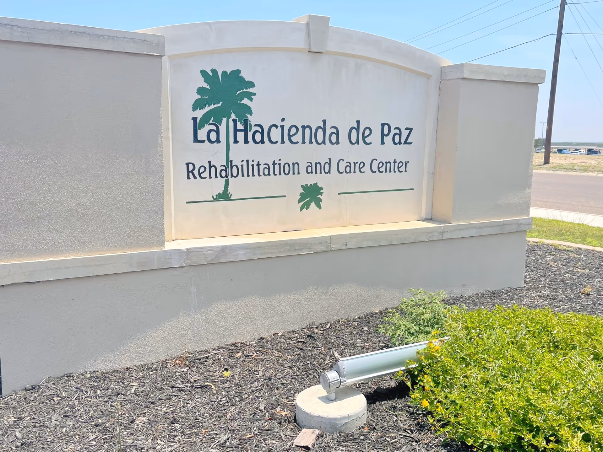 Entrance monument sign reading "La Hacienda de Paz Rehabilitation and Care Center" set in landscaped grounds.