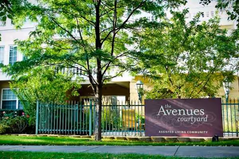 Exterior view of The Avenues Courtyard entrance with trees, gate, and building facade.