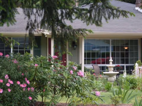 Front exterior of Royal Oak Adult Family Home, single-story with garden, fountain, and patio seating.