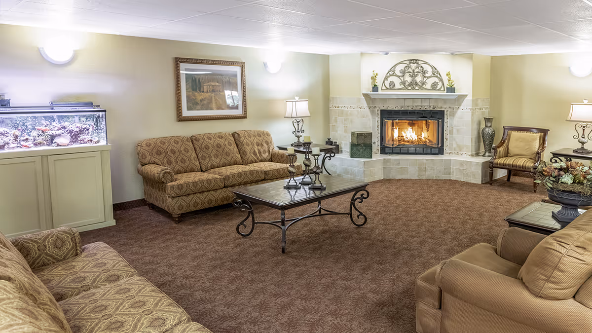 Cozy living room with patterned sofas, a coffee table, a lit fireplace, and an aquarium.
