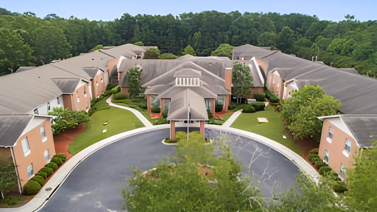 Aerial view of TerraBella Windsor Lake senior living facility showing a large U-shaped building surrounded by greenery and trees, with a circular driveway and entrance canopy in the center.