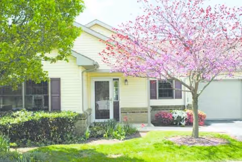 Front exterior of Creekside Residences with a blooming pink tree and landscaped lawn.