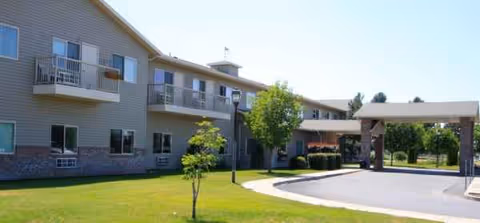 Exterior view of Sun Terrace Prosser building with balconies, green lawn, and driveway.
