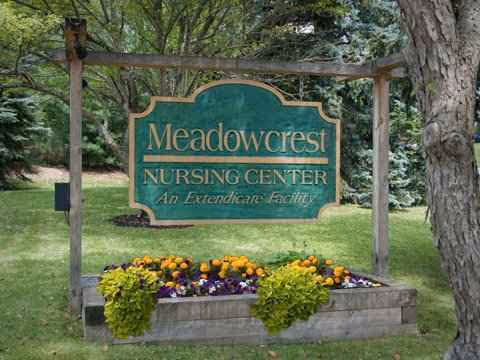 Meadowcrest Nursing Center exterior sign with flowering planters and trees.