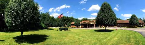 Exterior view of Huntsville Post-Acute and Rehabilitation Center with flag, trees, and green lawn.