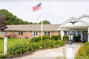 Grace Barker Health facility exterior with flagpole, brick facade, and landscaped entrance path