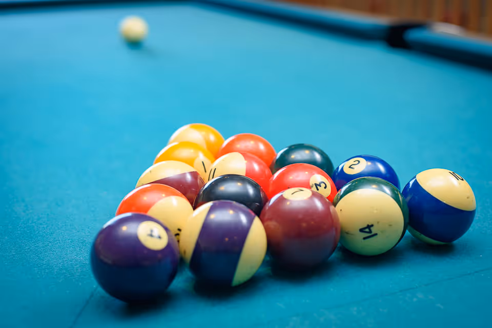 Close-up view of a rack of colorful billiard balls arranged on a green pool table, ready for a game of pool.
