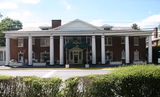 Mecklenburg House senior living building with columned entrance and green awning.