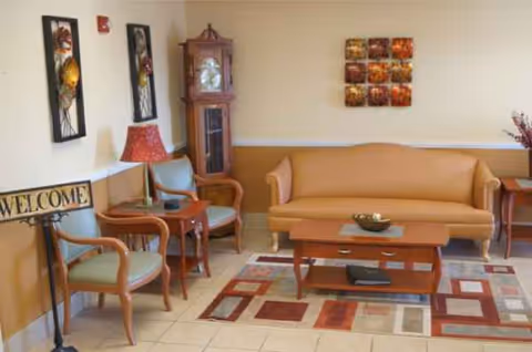 Cozy lobby seating area with sofa, chairs, coffee table, grandfather clock, and wall art.
