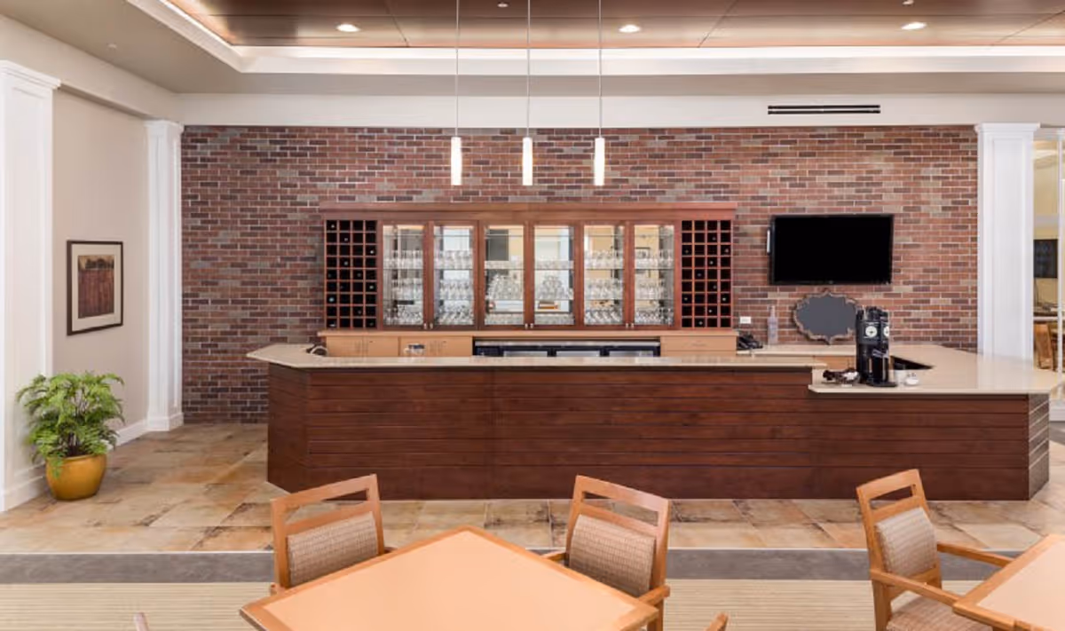 Spacious indoor dining/lounge area with a wooden service counter, brick accent wall with wine racks, and seating in the foreground.