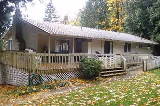 Single-story facility with a covered front porch, wooden railing, and fallen leaves on the lawn.