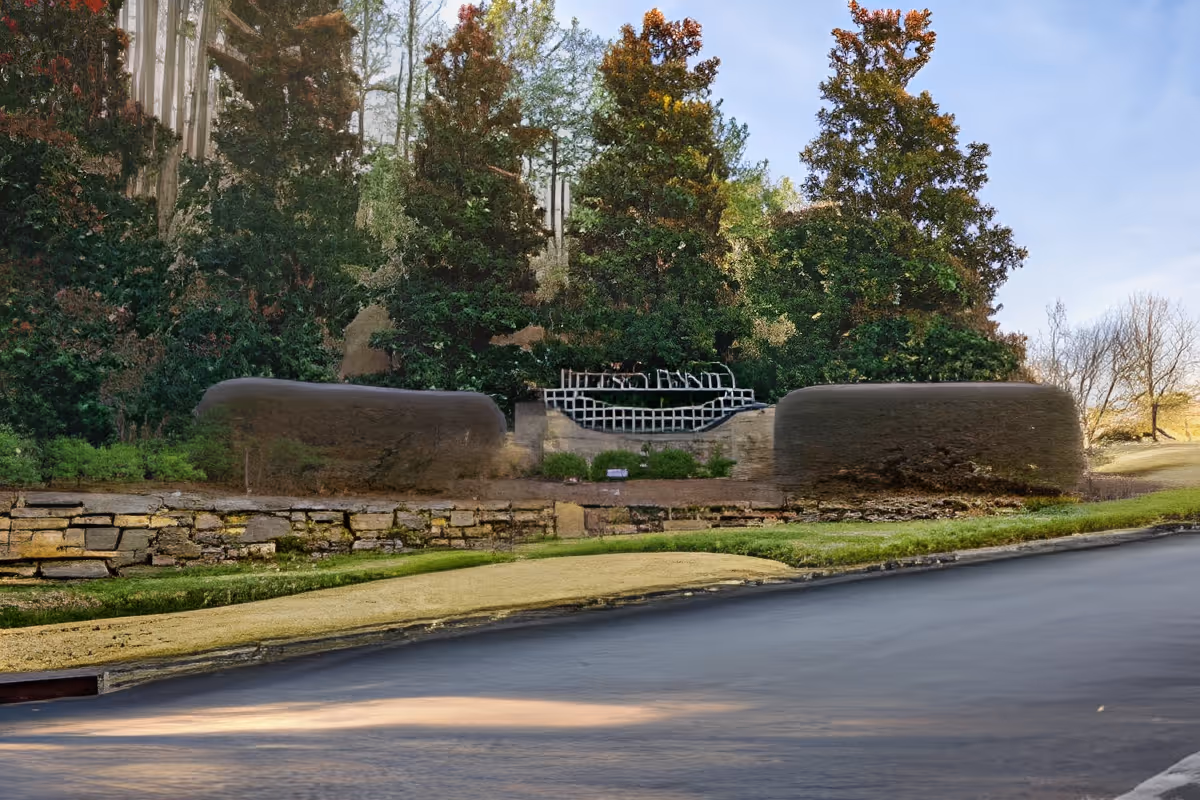 Stone and brick entrance sign for The Haven at Regency Pointe surrounded by trimmed bushes and tall trees under a clear sky.