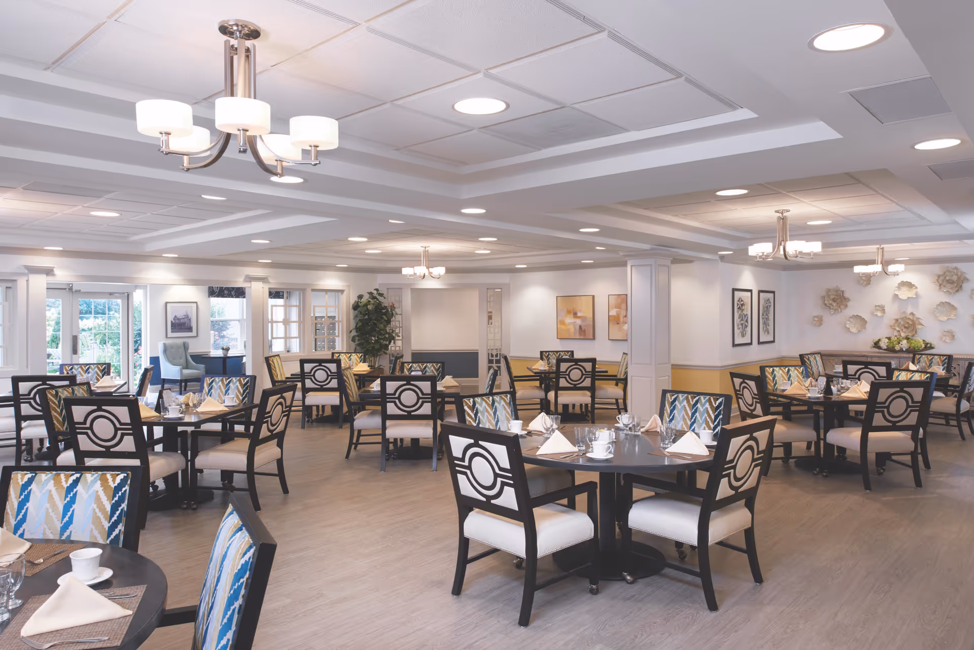 Bright, spacious dining room with multiple round tables and patterned chairs set for service.
