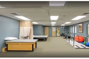 Spacious rehabilitation therapy room with treatment tables, parallel bars, exercise balls, and other physical therapy equipment.