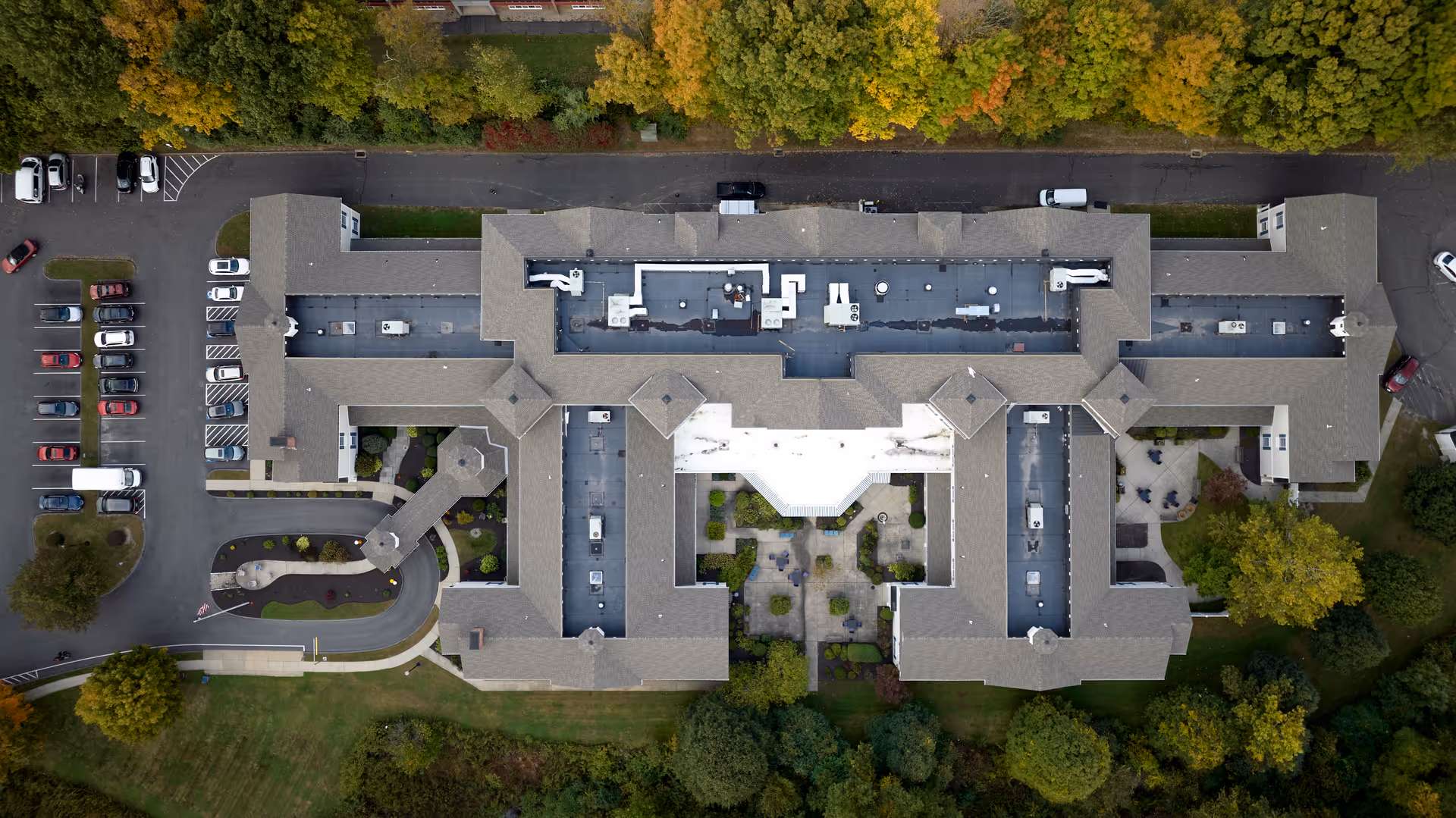 Aerial top-down view of a large residential complex with a central courtyard, parking areas, and surrounding trees.