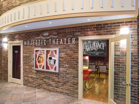 Brick-lined interior hallway entrance to the 'Majestic Theater' with movie posters and an open door revealing a popcorn cart and seating under a 'Casablanca' sign.