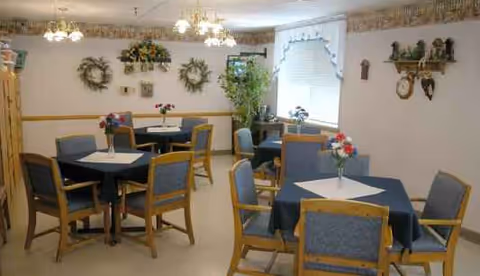 A dining room in a senior living facility with tables, chairs, and centerpieces.