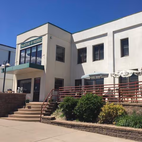 Exterior view of Traditions of Frederic with steps, railing, and outdoor seating.