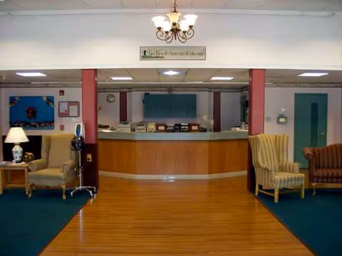 Reception desk with curved wood counter and seating area in a senior living facility lobby