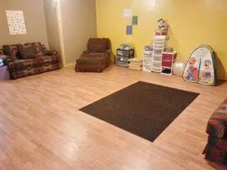 A spacious living room with brown couches, a dark rug, and yellow walls.