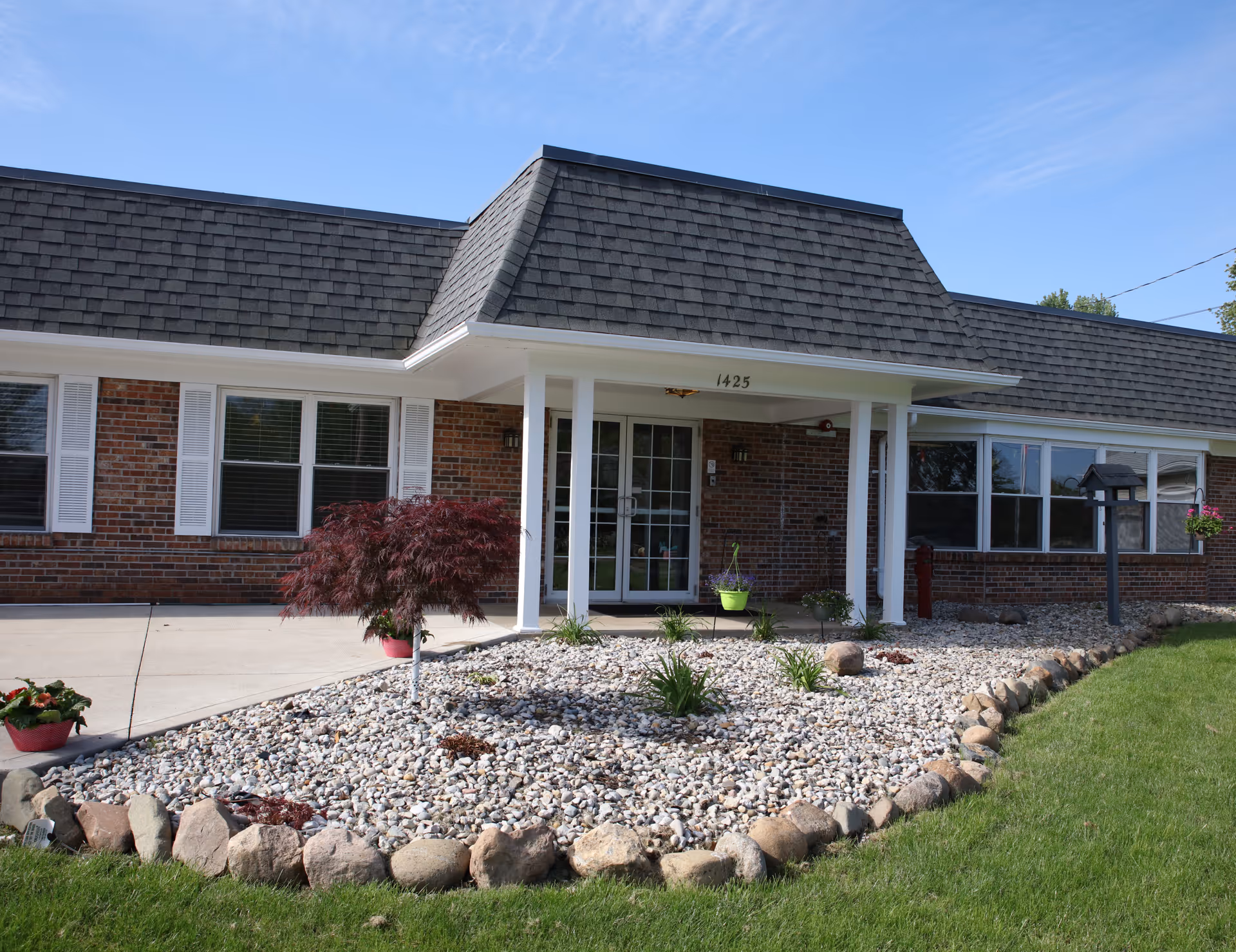 The exterior entrance of Hickory Creek at Huntington, featuring a landscaped area with decorative stones and plants.