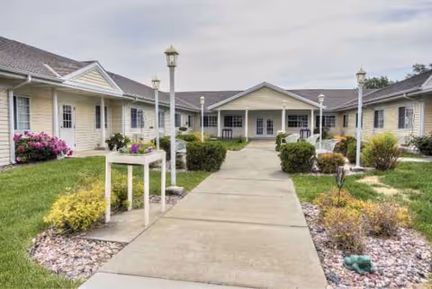 Front view of Cottonwood Senior Living with a central walkway, lamps, and landscaped entry.