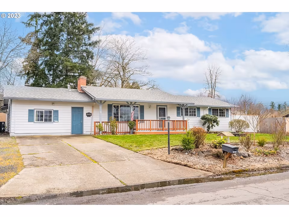 Single-story residence with a blue front door, porch railing, and manicured yard.