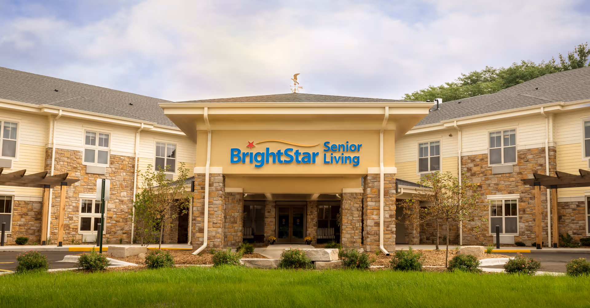 Front entrance of BrightStar Senior Living facility with a covered porte-cochère, sign above the entry, and landscaped lawn in front.