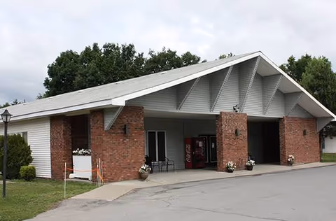 Brick building entrance with benches, planters, and a vending machine.