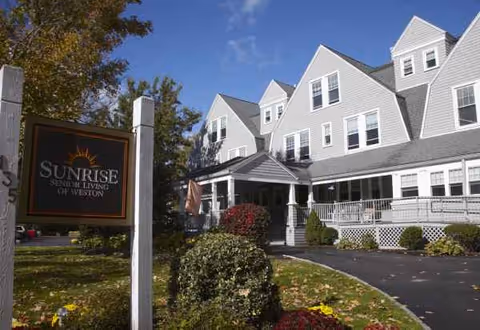 Exterior shot of Sunrise of Weston senior living facility with sign and landscaping.