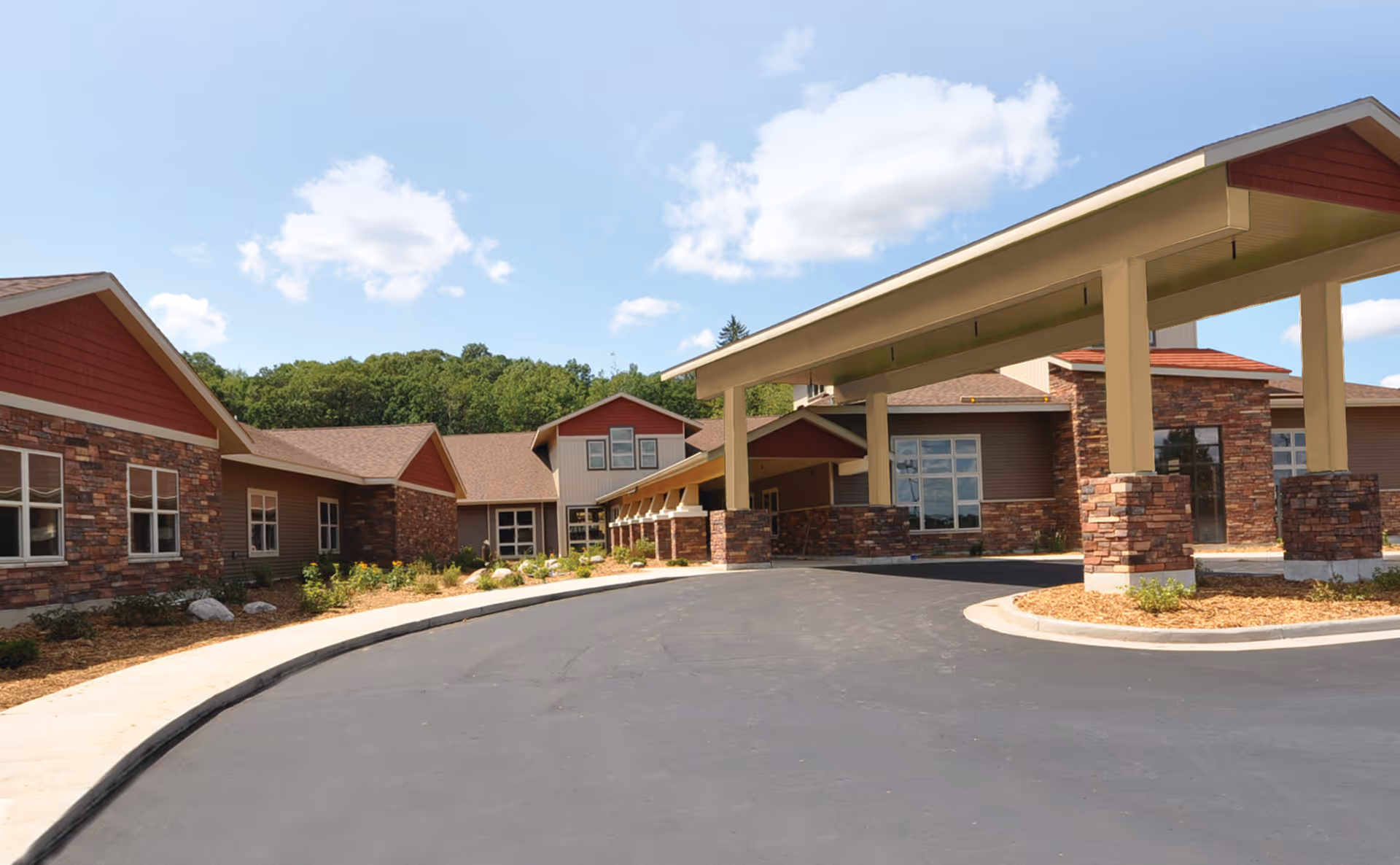 Exterior view of Dove Healthcare – South Assisted Living, featuring a covered entrance with stone columns along a curved driveway.