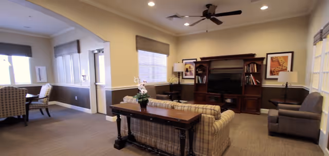 Common living room with a plaid sofa, armchairs, a wooden entertainment center with TV, and a small dining nook.