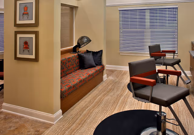 Interior seating area with salon-style chairs, a built-in cushioned bench, and framed artwork on the wall.