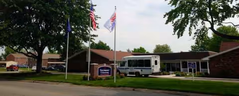 Exterior view of Seymour Crossing senior living facility with bus and flagpoles