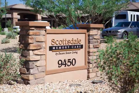 A stone front sign for Scottsdale Memory Care with address 9450, set against desert landscaping.