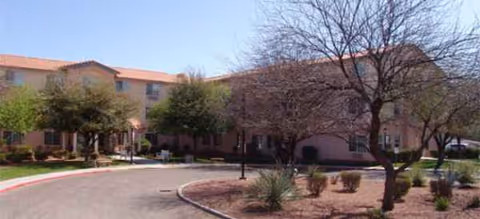 Exterior view of Avista Senior Living Tucson with beige building, drive, and trees.