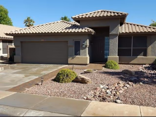 Front exterior view of a single-story assisted living facility with desert landscaping and a two-car garage.