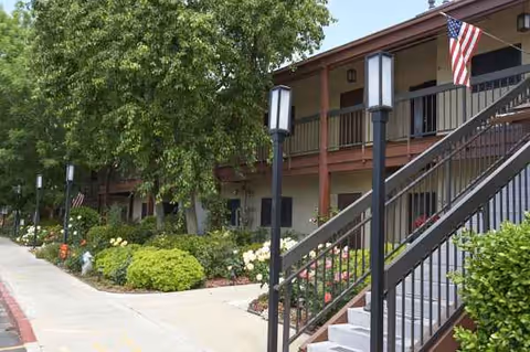 Exterior view of Health Center at Rosewood, showing stairs, walkway, landscaping, and flags.