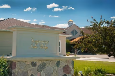 Exterior view of Temperance Lake Ridge Senior Living with a stone sign and building