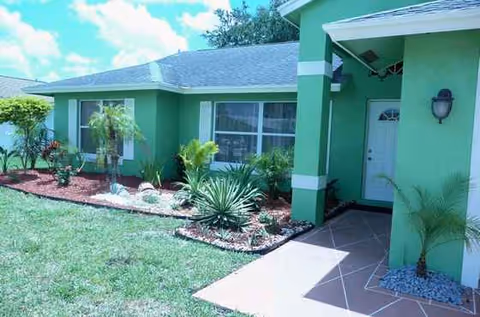 Meadow Lark Inn exterior: green, single-story facility with landscaped entrance and walkway.