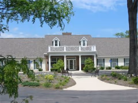 Exterior view of Abbington of Arlington, a senior living facility with central entrance and landscaped front.