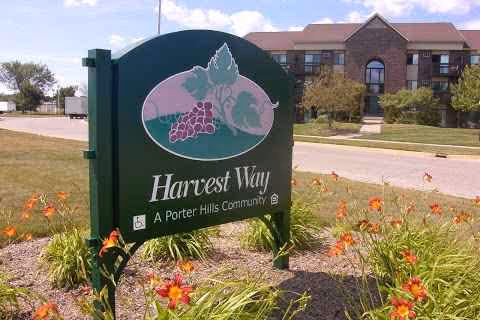 Green Harvest Way Retirement Community sign in front of a landscaped yard and brick building.