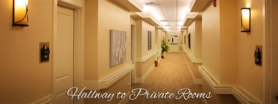 Carpeted, well-lit interior hallway with doors on both sides, wall lights, and decorative artwork.