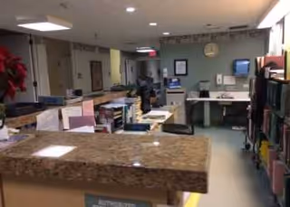 Reception area inside a senior living facility with granite counter and staff at desks.