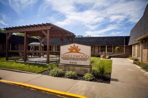 Exterior view of Tanglewood Nursing & Rehabilitation sign, pergola, and entrance walkway.