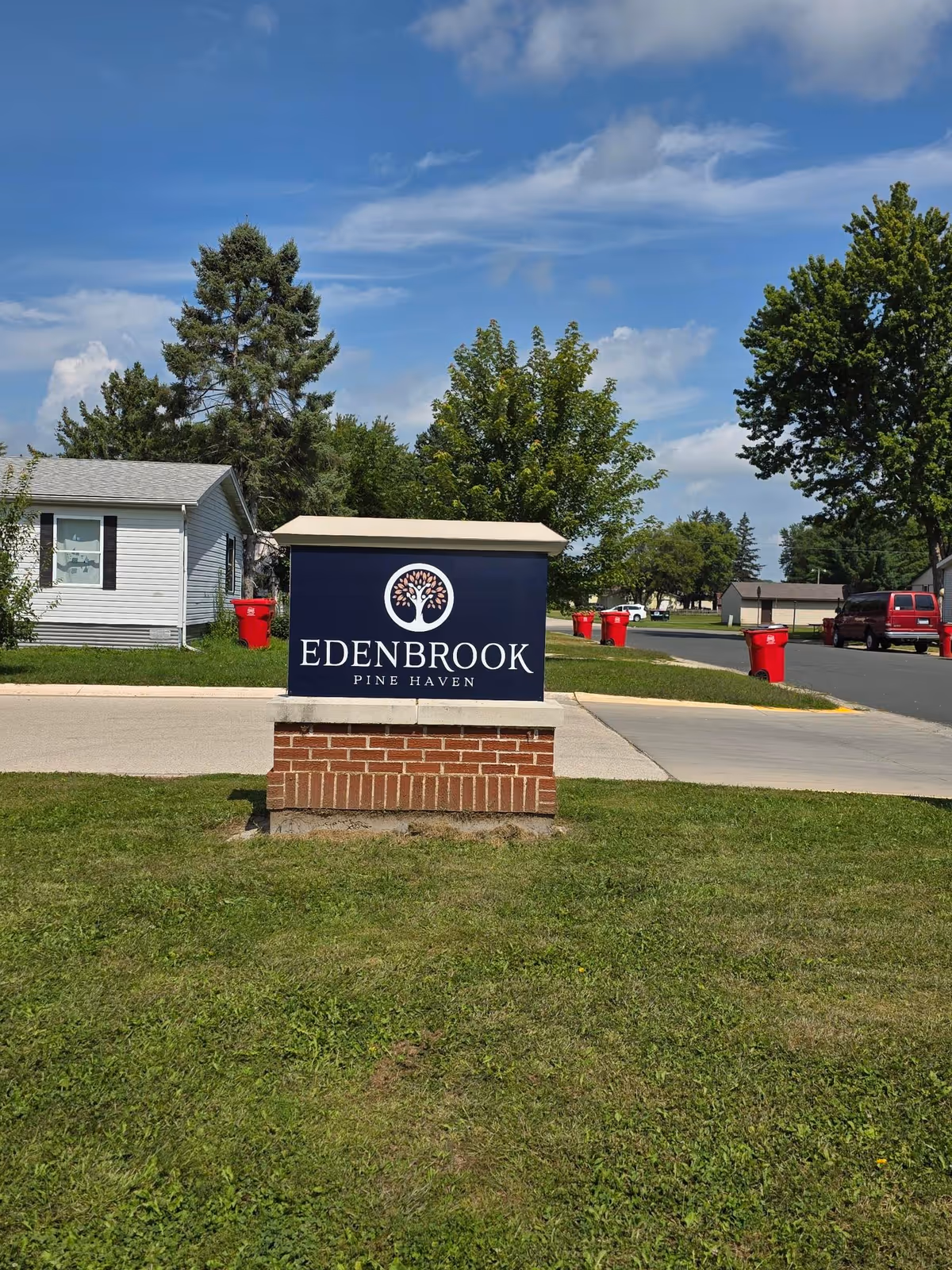 A sign for Edenbrook Pine Haven is displayed in a green outdoor area.