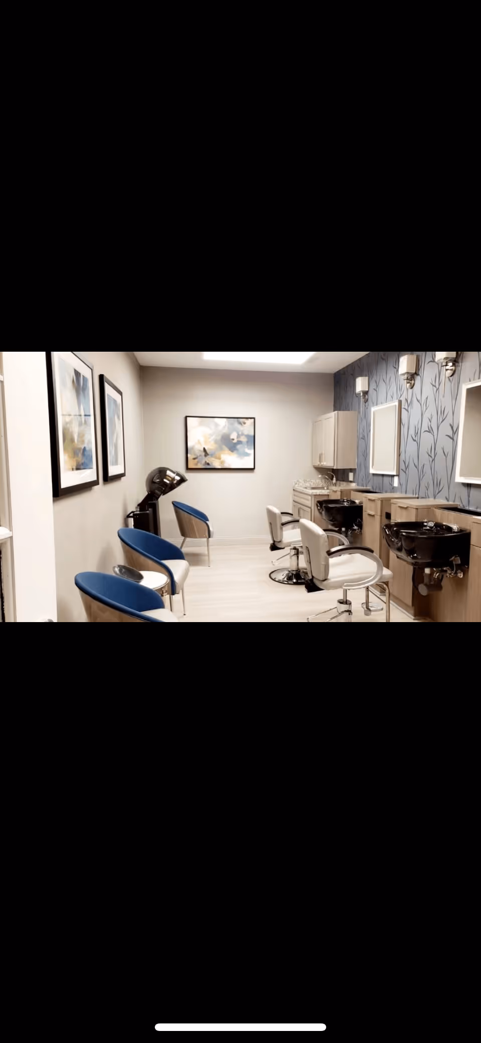 Small salon-style room with styling chairs, shampoo sinks, mirrors, and waiting chairs.