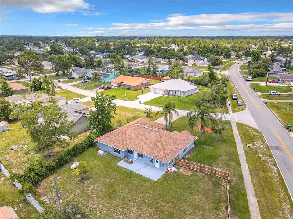 Aerial view of a single-story house with a brown roof in a suburban neighborhood.